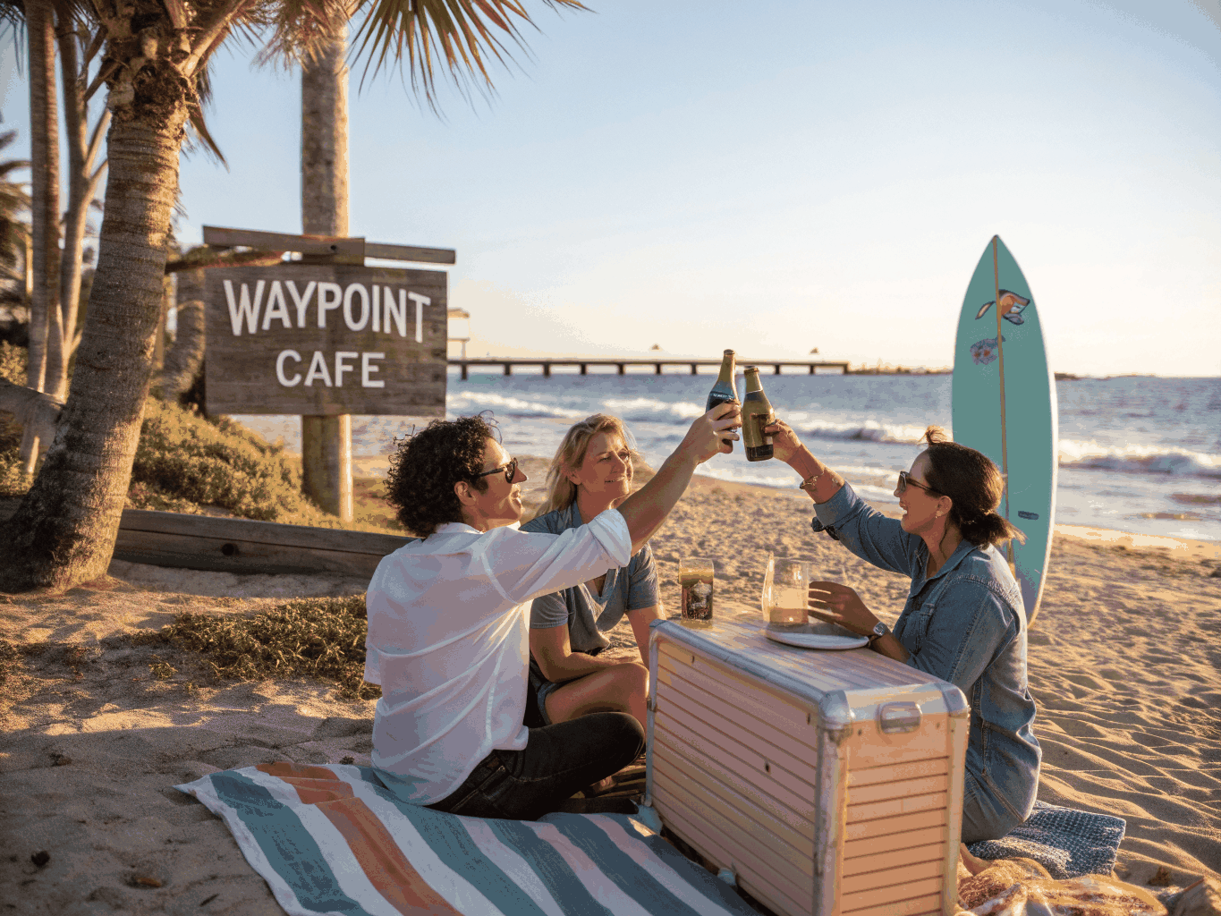 Women toasting cold citrus spritz cocktails with ocean waves in the background on Clearwater Beach